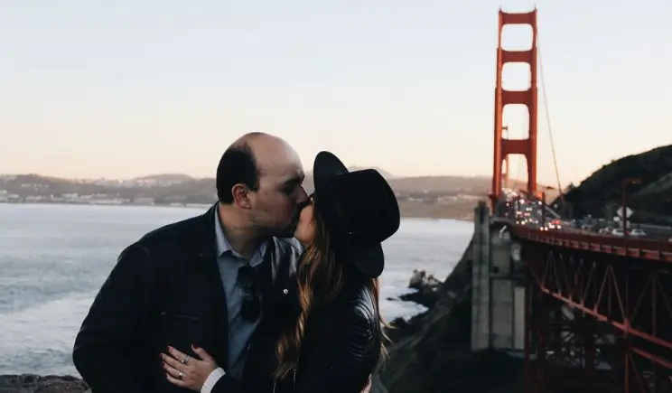 homem e mulher se beijando ao lado da ponte golden gate durante o dia