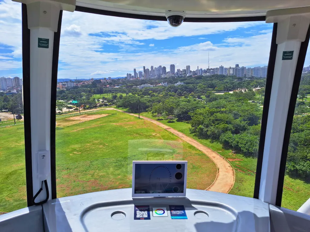 Vista panorâmica de São Paulo a partir de uma cabine da roda gigante do Parque Villa Lobos, mostrando áreas verdes e a cidade ao fundo.