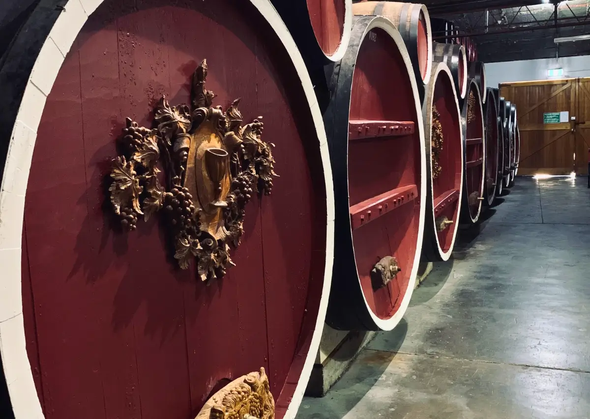 Barricas de vinho grandes e decoradas em uma adega na região vinícola australiana.